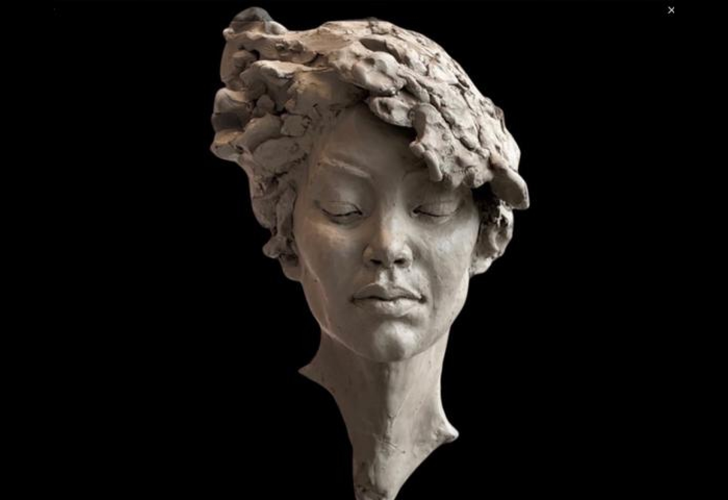 Clay sculpture of a serene woman's face.